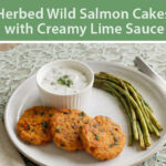 Herbed wild salmon cakes with creamy lime sauce and roasted asparagus on a plate