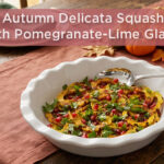 Roasted delicata squash rounds topped with pomegranate arils and fresh parsley in a serving bowl on an autumn table